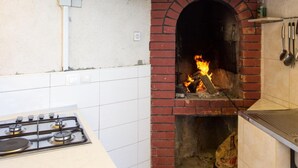 Una cocina con horno de ladrillo, estufa a gas y utensilios de cocina colgantes.