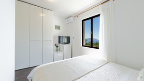 Ein Schlafzimmer mit Bett, Fernseher, Schreibtisch und Fenster mit Blick.