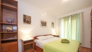 Une chambre à coucher comprenant un lit, des tables de chevet, une commode en bois et une étagère avec des objets décoratifs.