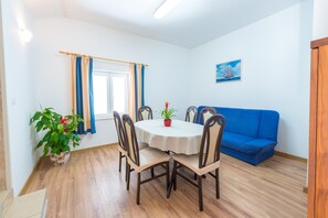 A dining area with a round table, chairs, a blue sofa, and a potted plant.