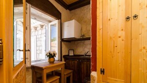 Cocina compacta con armarios de madera, horno empotrado y una pequeña mesa de comedor con un jarrón de flores.
