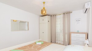 Une chambre à coucher comprenant un lit, une armoire, un miroir, un lustre et un climatiseur fixé au mur.
