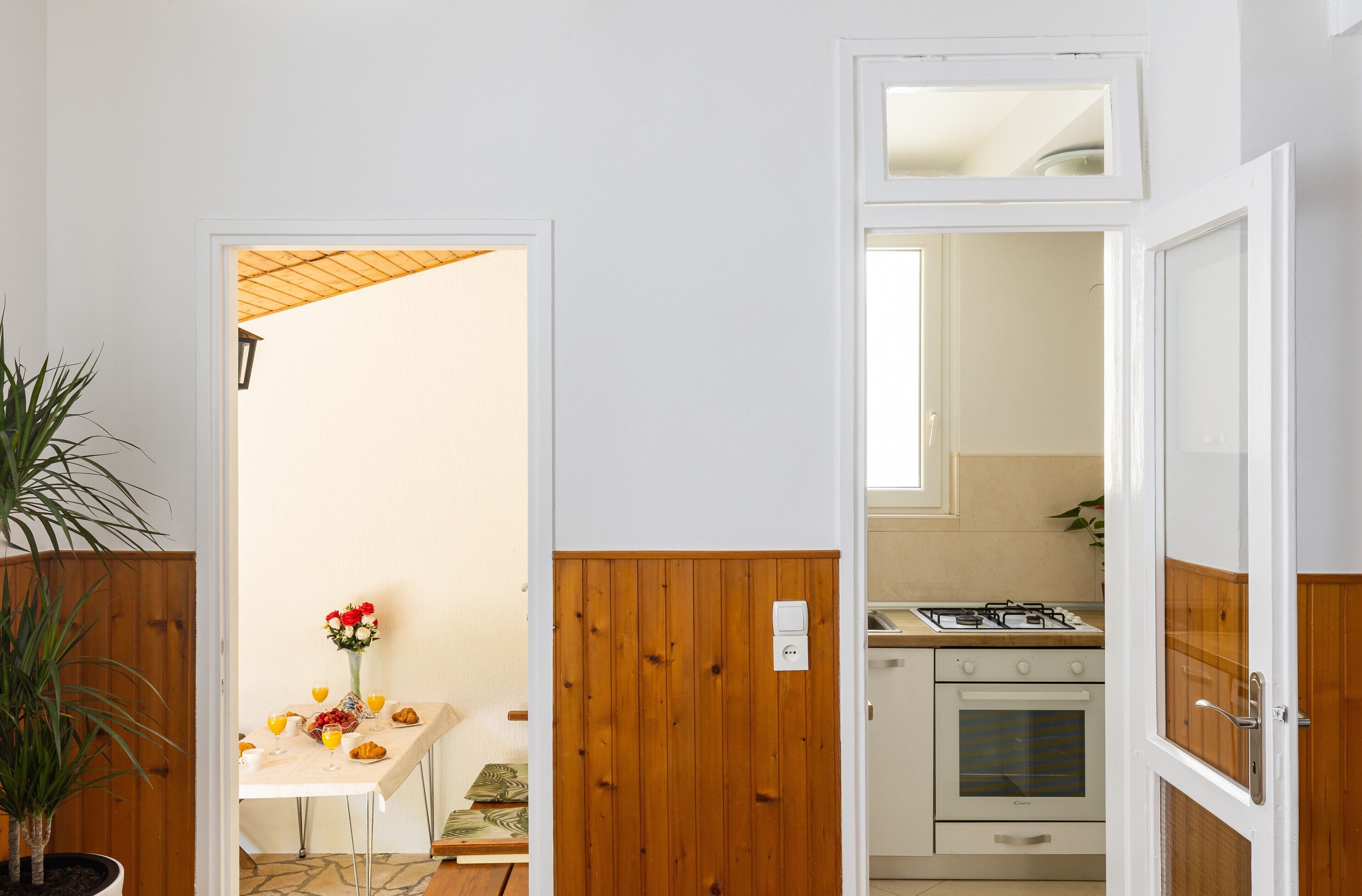 A kitchen with a stove, oven, and a dining area with a table set for breakfast.