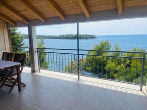 A balcony with a view of the sea, a table with chairs, and a railing. - Apartments Bačić - Two Bedroom Apartment with Sea View (Blato)