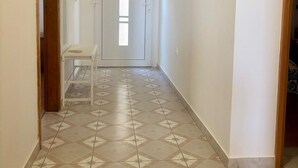 Un passadís amb rajoles de terra estampades, una porta blanca amb finestra i una unitat de climatització a la paret.