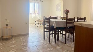 Zona de dinar amb taula rodona, cadirees, taula auxiliar petita i una planta en test.