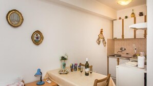 Eine kleine Küche mit Esstisch, einem kleinen Kühlschrank und einer Spüle.