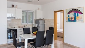 Une cuisine moderne avec des meubles blancs, une table à manger avec des chaises et un réfrigérateur.