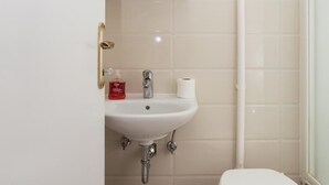 Une petite salle de bain avec un lavabo blanc, des toilettes et un miroir au-dessus du lavabo.