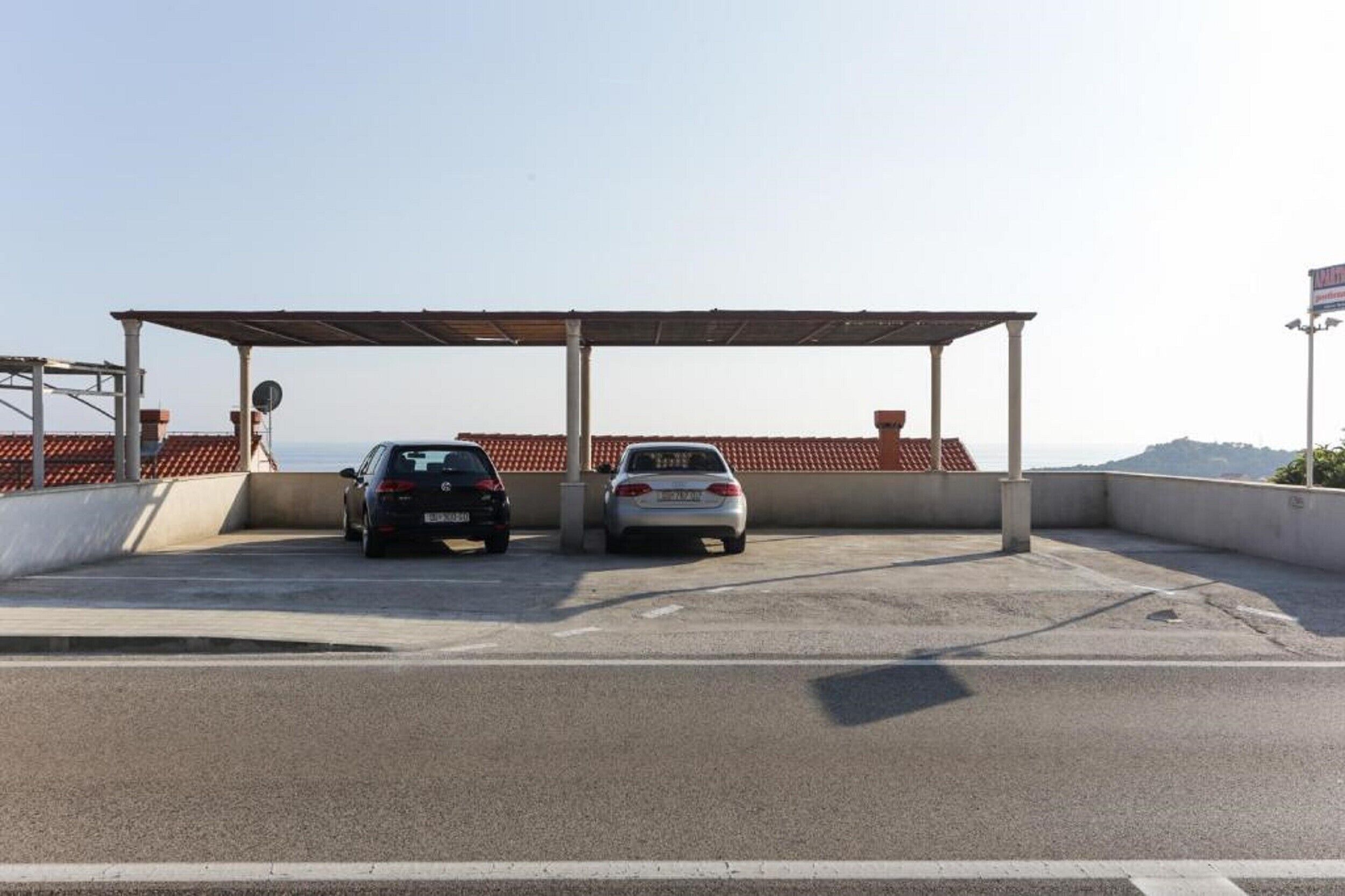 A parking area with two cars and a covered structure.