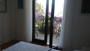 Une chambre à coucher avec un lit, une fenêtre et une vue sur un balcon orné de fleurs.