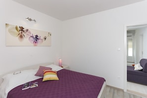 A bedroom with a bed, pillows, a bedside table with a lamp, and a wall art piece. - Apartments Posta - One-Bedroom Apartment with Terrace and Sea View (Saplunara)