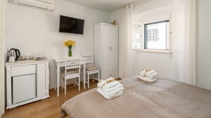 Een hotelkamer met een bed, een bureau met stoelen, een televisie, een kledingkast en een raam met gordijnen.