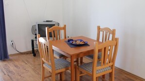 Un coin repas avec une table en bois et quatre chaises, une petite télévision et des tableaux encadrés accrochés au mur.