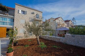 Una zona residencial con edificios de piedra, un árbol y un patio con mobiliario exterior.