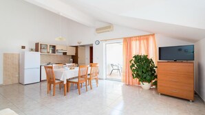 A compact apartment with a kitchenette, dining area, and a living space with a TV and a plant. - Apartments Ana & Bogdan - One Bedroom Apartment with Balcony and Sea View (A2) (ST) (Postira)