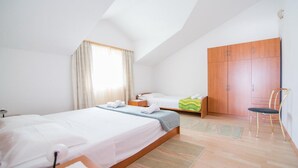 A hotel room with two beds, a wooden wardrobe, a chair, and a window with curtains. - Apartments Ana & Bogdan - One Bedroom Apartment with Balcony and Sea View (A2) (ST) (Postira)