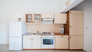 A compact kitchen with white cabinets, a built-in oven, a sink, and a coffee maker. - Apartments Ana & Bogdan - One Bedroom Apartment with Balcony and Sea View (A2) (ST) (Postira)