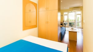 A room with wooden cabinets, a bed with a blue and white bedspread, and a window with a view of the outdoors.