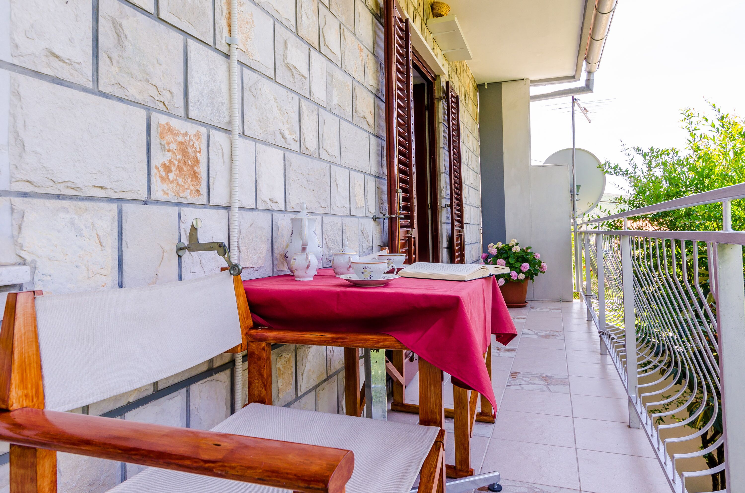 Ein Balkon mit Tisch für zwei Personen, einem Blumentopf und einem weißen Geländer.