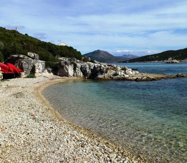 Enjoy a serene beach experience with calm waters and a picturesque hillside backdrop.