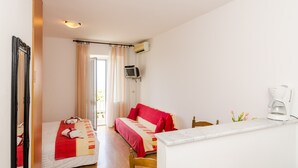 Une chambre d’hôtel avec deux lits, une télévision, une machine à café et une fenêtre avec des rideaux.