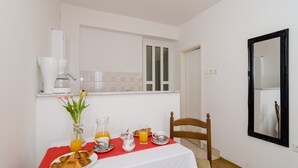 Une table de petit-déjeuner dressée avec des croissants, du jus d’orange et un vase rempli de fleurs.