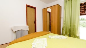 Un dormitorio con cama, un armario de madera, un radiador y una ventana con cortinas.