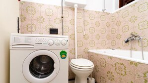 Un baño pequeño con lavadora, inodoro y bañera.