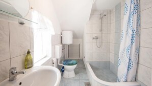 A bathroom with a bathtub, toilet, and sink. - Apartments Jasenka - Studio Attic with Terrace and Sea View (Supetar)