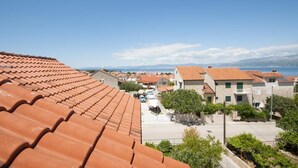 A coastal residential area with terracotta-tiled roofs, a clear sky, and a view of the sea. - Apartments Jasenka - Studio Attic with Terrace and Sea View (Supetar)