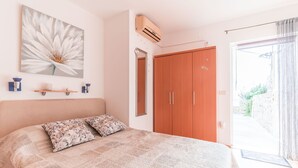 A bedroom with a large bed, a wardrobe, a mirror, and a wall-mounted air conditioner. - Studio Maro - Studio Apartment with Terrace (Dubrovnik)