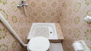Ein Badezimmer mit Dusche, Toilette und einem kleinen Waschbecken.