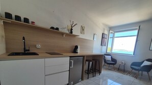 Een moderne keuken met een inbouwvaatwasser, een koffieapparaat en een klein barretje met krukjes.