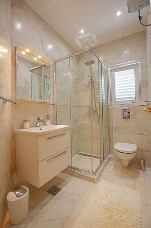 Enjoy a refreshing shower in the walk-in shower with a large mirror above the vanity.