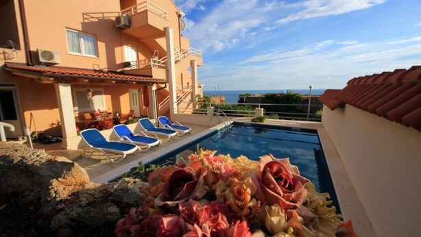 A pool area with lounge chairs and a view of the sea. - Apartment Ana - Four Bedroom Apartment with Terrace and Private Pool (Cavtat)
