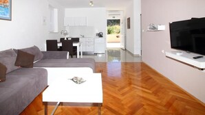 A modern living room with a grey sofa, a white coffee table, and a flat-screen TV mounted on the wall.