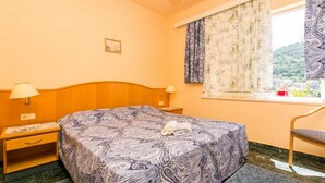 A bedroom with a bed, nightstands, a window with curtains, a chair, and a view of a mountain. - Apartments Elelu-Two-Bedroom Apartment with Terrace (Dubrovnik)