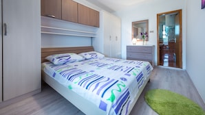 Een slaapkamer met een bed, een kast, een spiegel en een deur naar een badkamer.