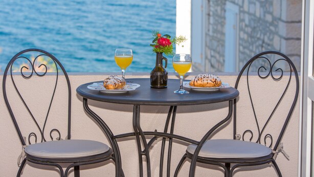 A round table with two chairs, a bottle, and two glasses of orange juice. - Apartments Tino- Two Bedroom Apartment with Balcony and Sea View (Sutivan)