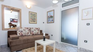 A living room with a brown sofa, a white coffee table, and a fluffy rug. There are framed pictures on the wall and a large mirror above the sofa. - Apartments Tino- Two Bedroom Apartment with Balcony and Sea View (Sutivan)