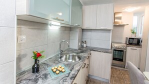 A modern kitchen with a marble countertop, stainless steel sink, and a microwave. - Apartments Tino- Two Bedroom Apartment with Balcony and Sea View (Sutivan)
