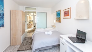 A modern hotel room with a bed, a desk with a laptop, and artwork on the walls. - Apartments Tino- Two Bedroom Apartment with Balcony and Sea View (Sutivan)
