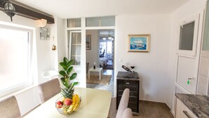A dining area with a table set for two, a fruit bowl, and a view into the adjacent room. - Apartments Tino- Two Bedroom Apartment with Balcony and Sea View (Sutivan)