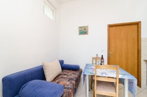Une petite pièce avec un canapé bleu, une porte en bois et une table entourée de chaises.