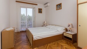 A bedroom with a wooden bed, a nightstand with a lamp, a wardrobe, and a window with curtains.
