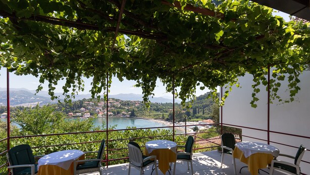 A terrace with a table and chairs, overlooking a scenic view of a lake and mountains.