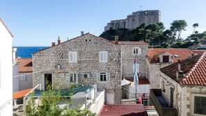 Un bâtiment en pierre avec un toit recouvert de tuiles rouges, un drapeau et une vue sur un fort historique.