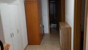 Een gang met een witte inloopkast, een houten kast en een betegelde vloer.