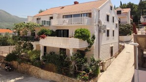 A two-story building with a balcony and a garden area. - Apartments Magda- Backside Studio Apartment (Cavtat)